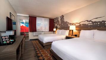 A hotel room with two beds, a desk with a coffee machine, and a view of a mountain through the window.