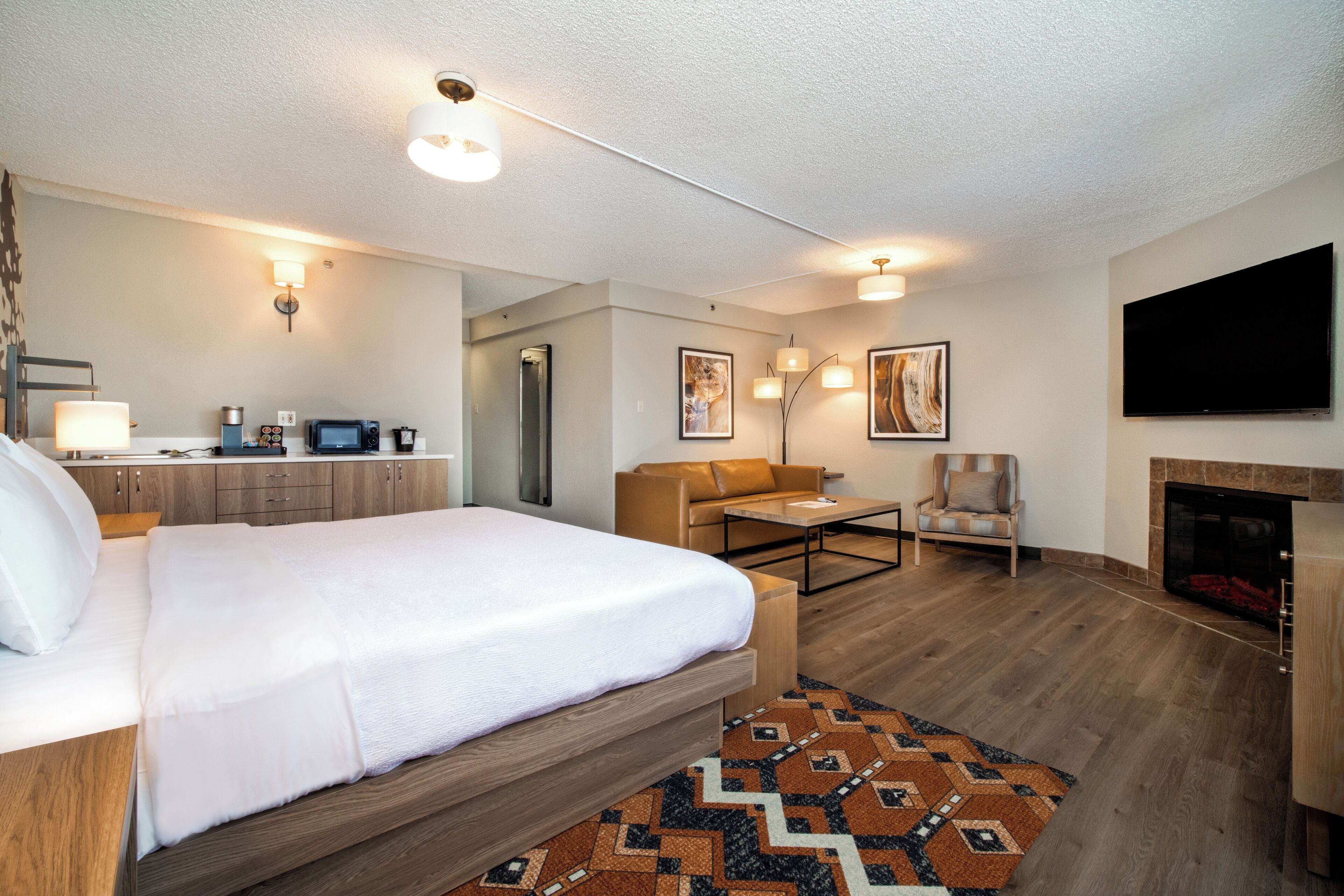 Una moderna camera d'hotel con un letto grande, un divano, un tavolino da caffè, un camino e una televisione a schermo piatto.