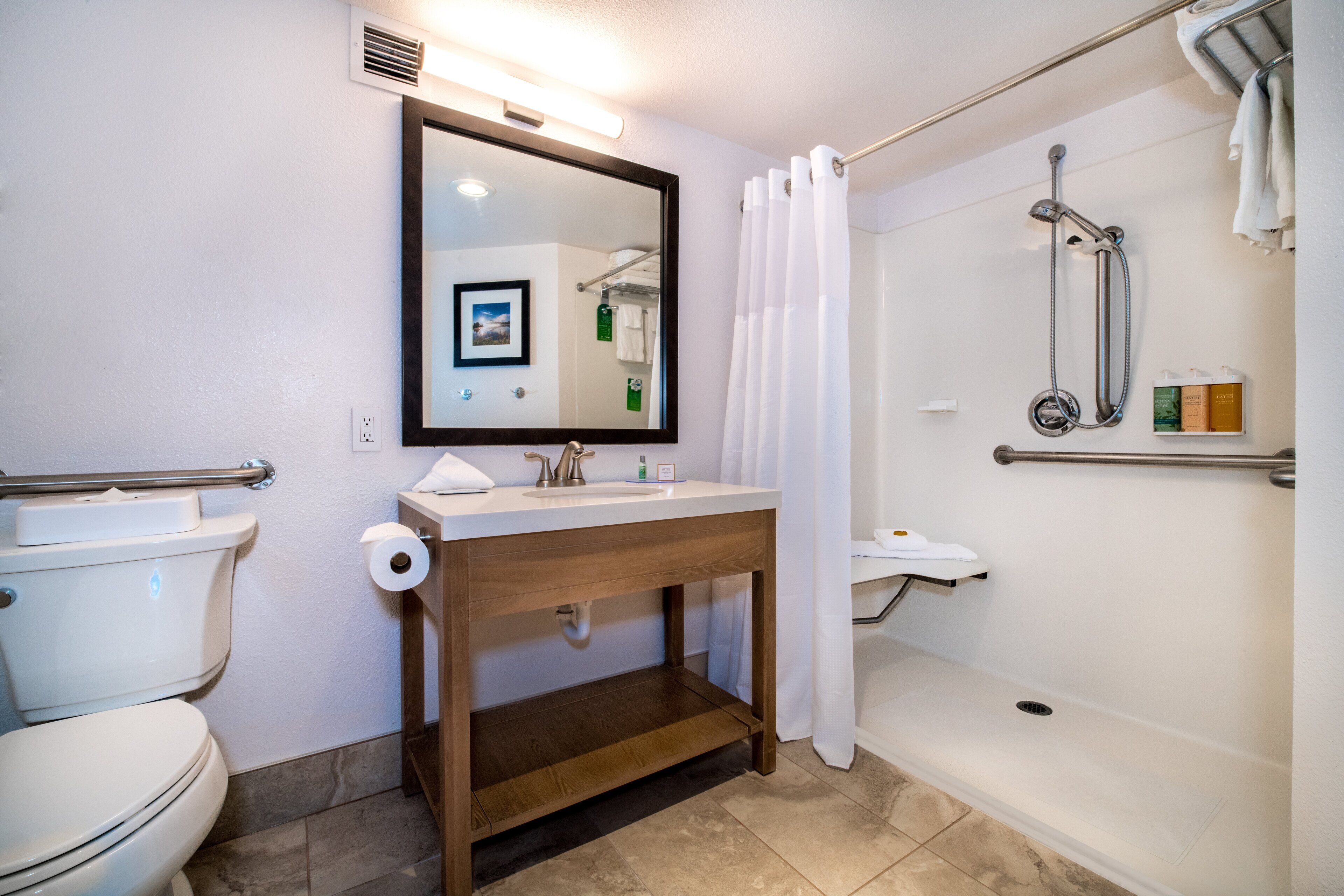 Une salle de bain comprenant des toilettes, un lavabo, un miroir, une douche et un porte-serviettes.