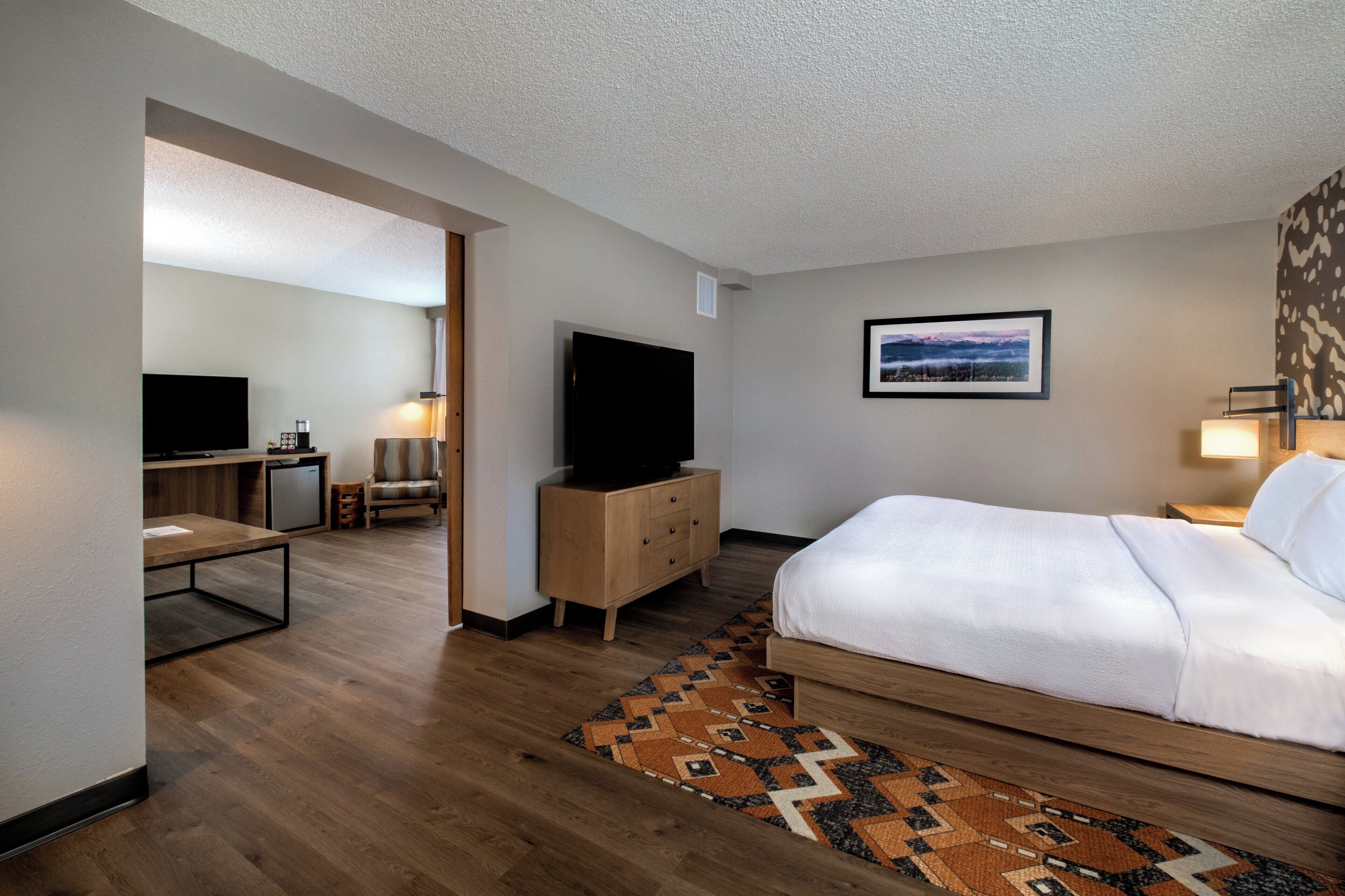 Una habitación de hotel con cama, televisión, escritorio y silla.