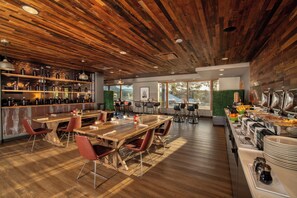 A modern dining area with wooden tables and chairs, a buffet with various food items, and a view of the outdoors. - Holiday Inn Estes Park by IHG (Estes Park)