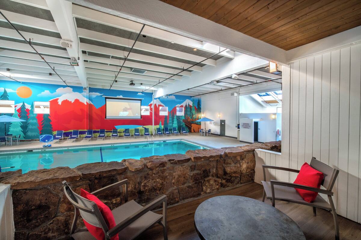 Una piscina interior con un mural, pared de piedra y zona de estar.