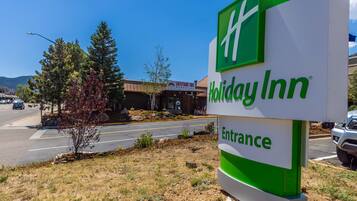 A Holiday Inn entrance sign with a clear view of the surrounding area including a road, a building labeled 'Latitude 105', and some trees.