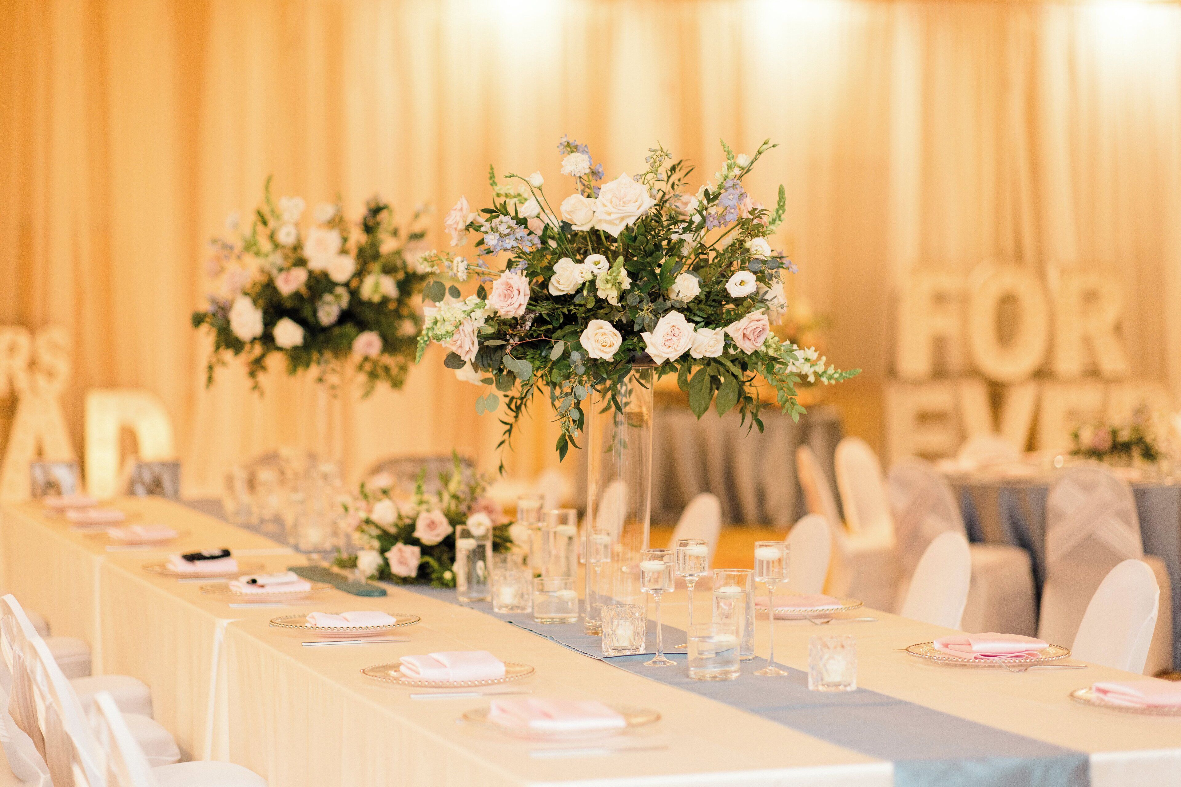 A long banquet table set with floral centerpieces, clear glassware, and neatly arranged place settings.
