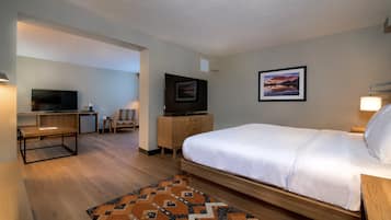 Una camera d'albergo con un letto, una scrivania, una televisione e un quadro appeso al muro.