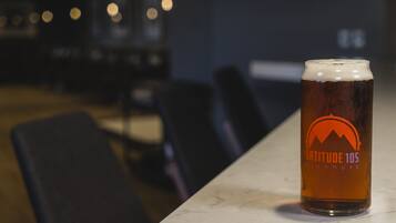 Un got de cervesa amb un logotip sobre un taulell de marbre en una habitació poc il·luminada amb cadires.
