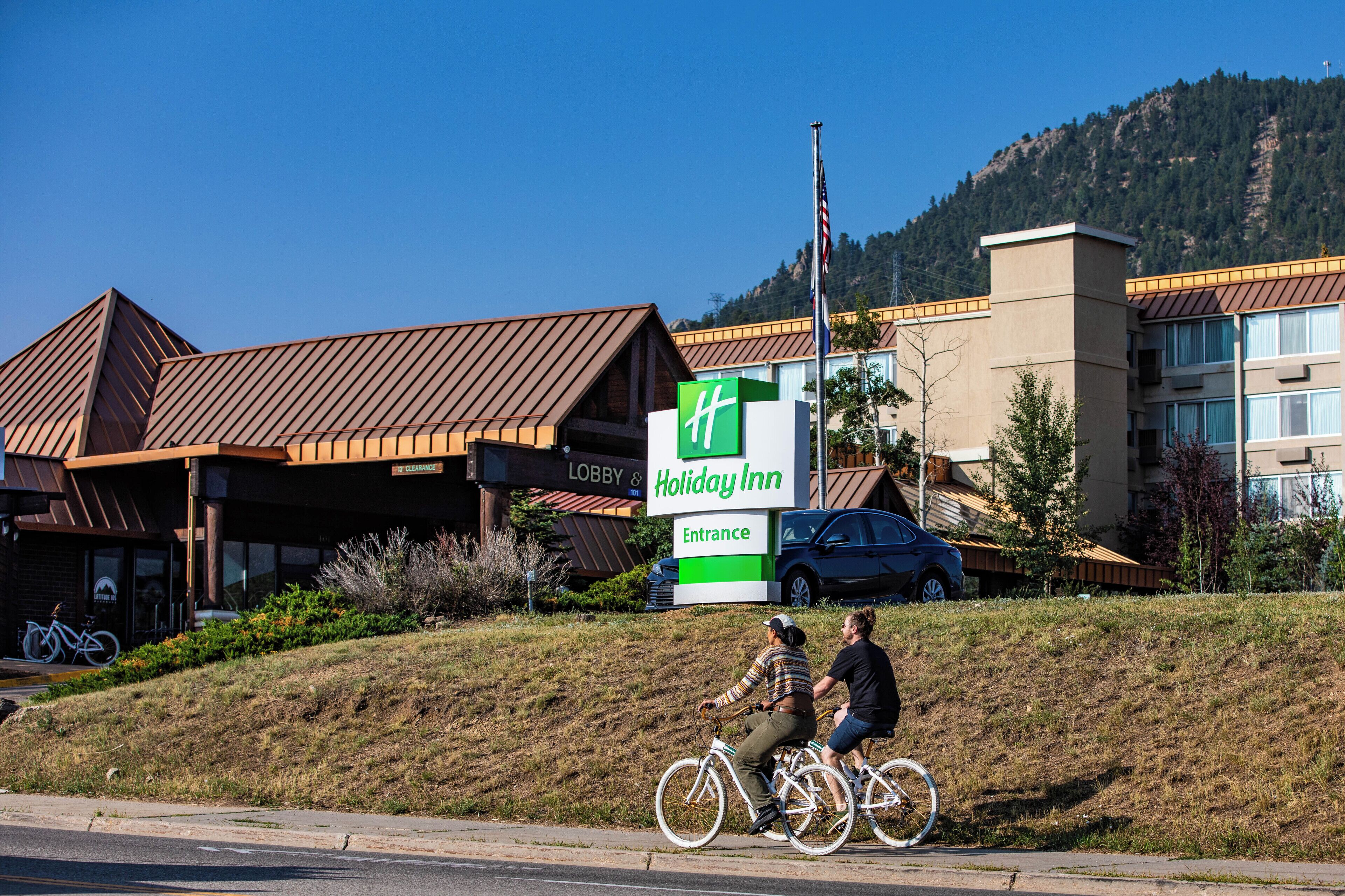 Een Holiday Inn bord met een duidelijke ingang en een berg op de achtergrond.