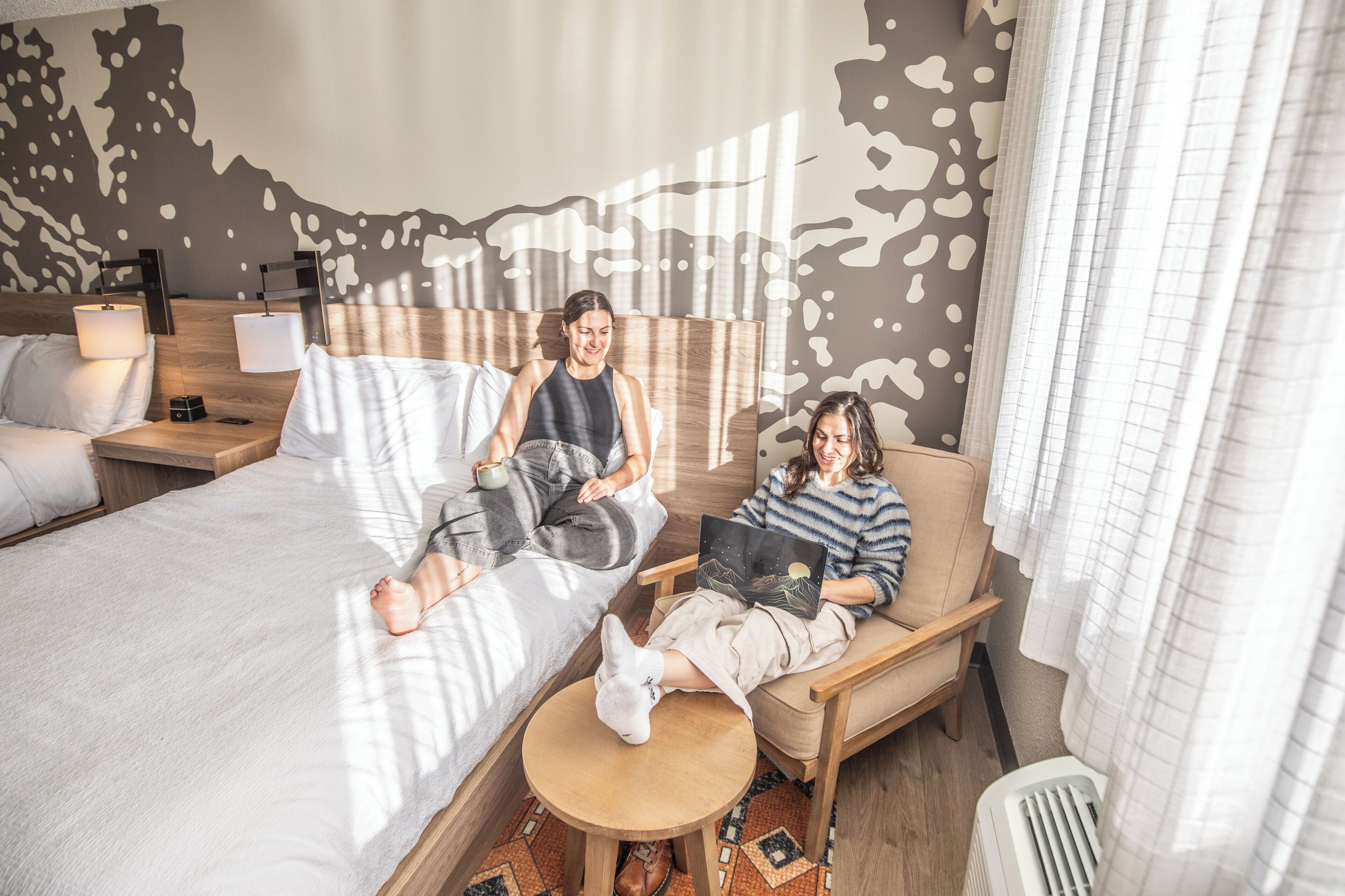 A modern hotel room with a large bed, a sofa, and a small round table.