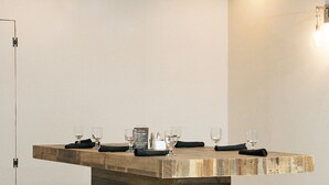 A wooden dining table with benches, glasses, and a menu in a modern interior.