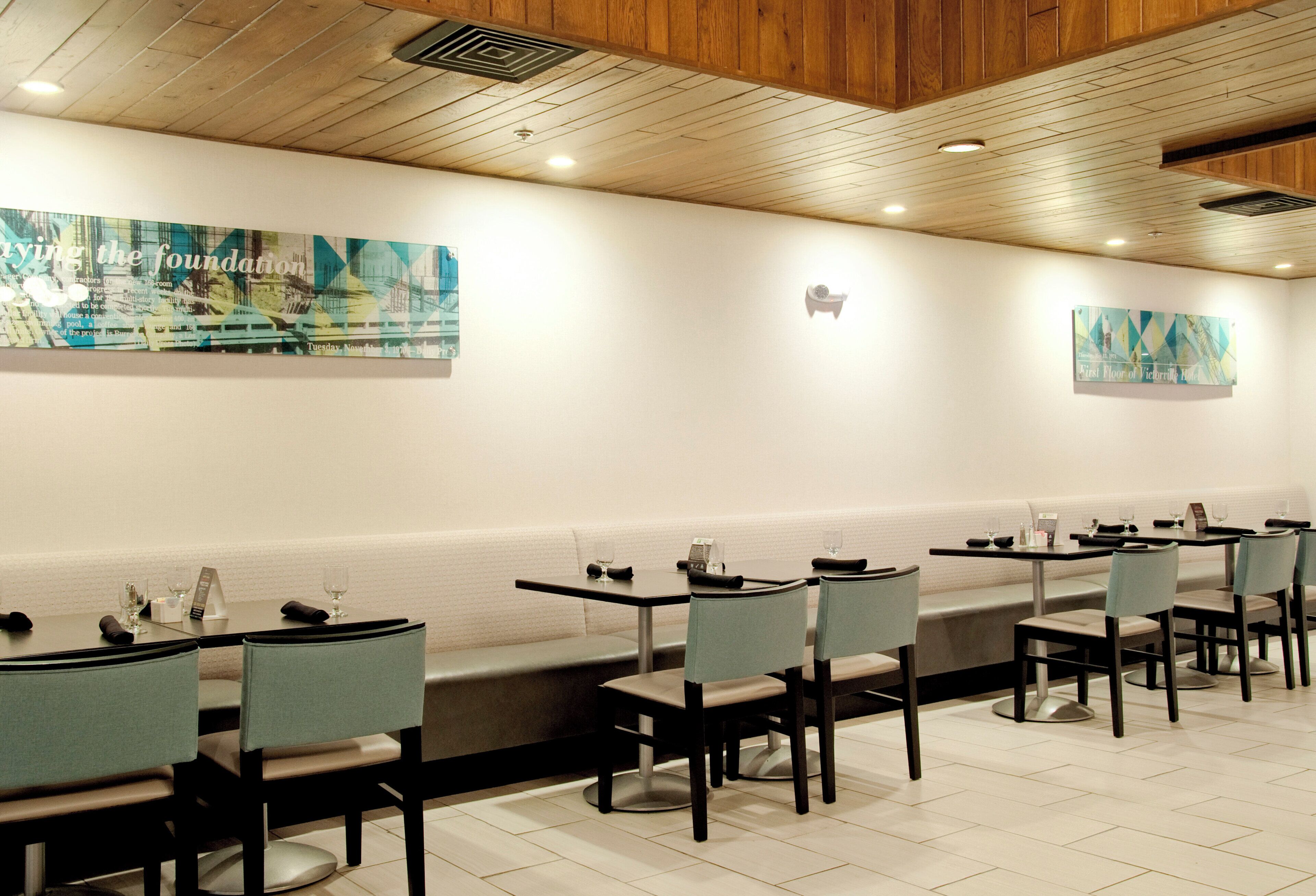 A restaurant with booths and tables, wooden ceiling, and wall art.