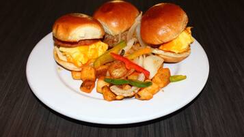 A plate with three burgers and a side of fried vegetables.