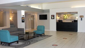 A modern lobby with a sofa, armchairs, a coffee table, a reception desk, and a flat-screen TV. - Holiday Inn Victorville by IHG (Victorville)