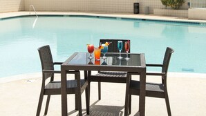 A poolside area with a table and chairs, a pool, and a building in the background. - Holiday Inn Victorville by IHG (Victorville)