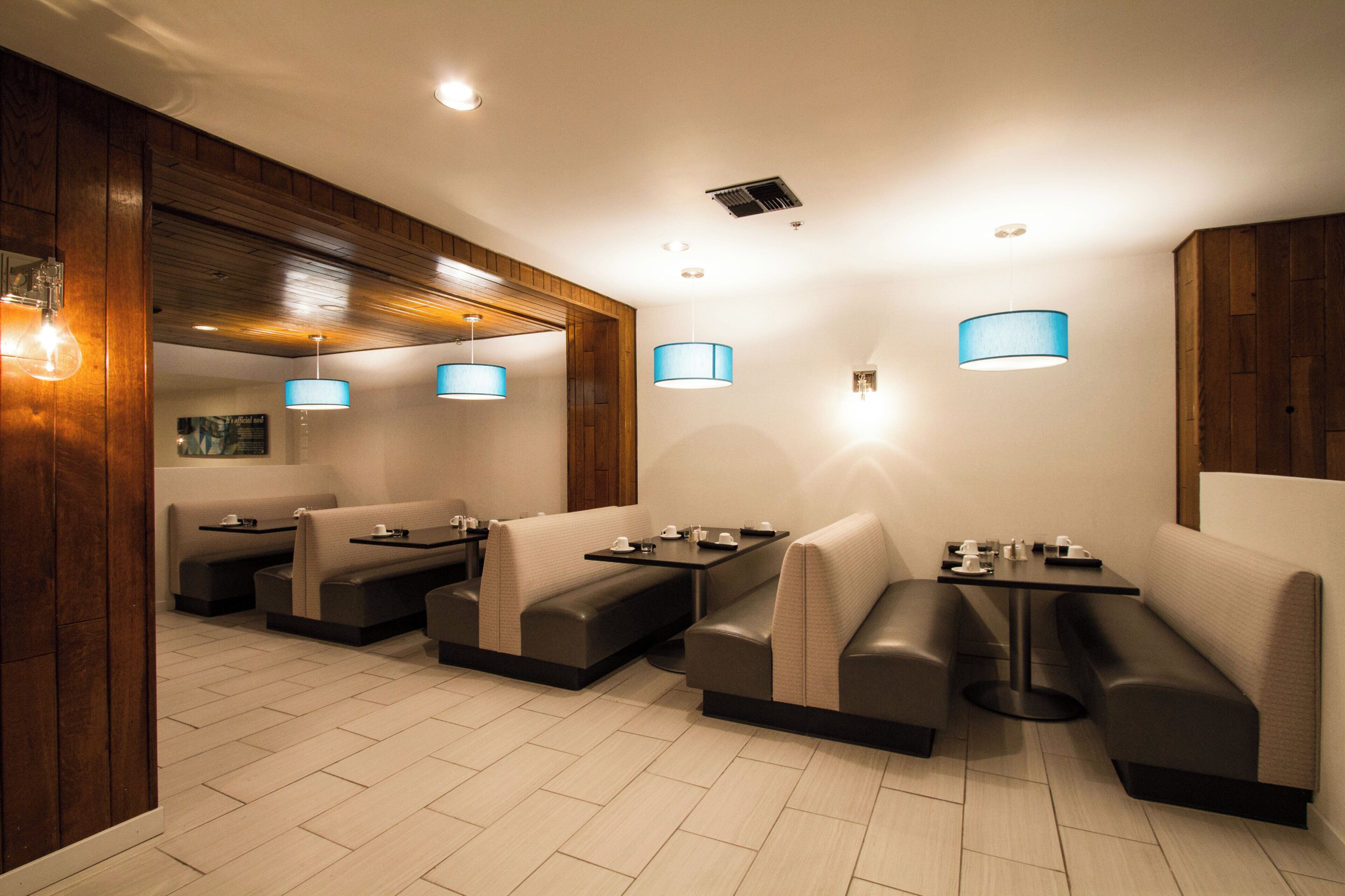 A restaurant with booth seating, pendant lighting, and a wooden accent wall.