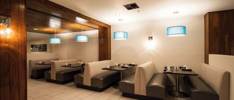 A restaurant with booth seating, pendant lighting, and a wooden accent wall.