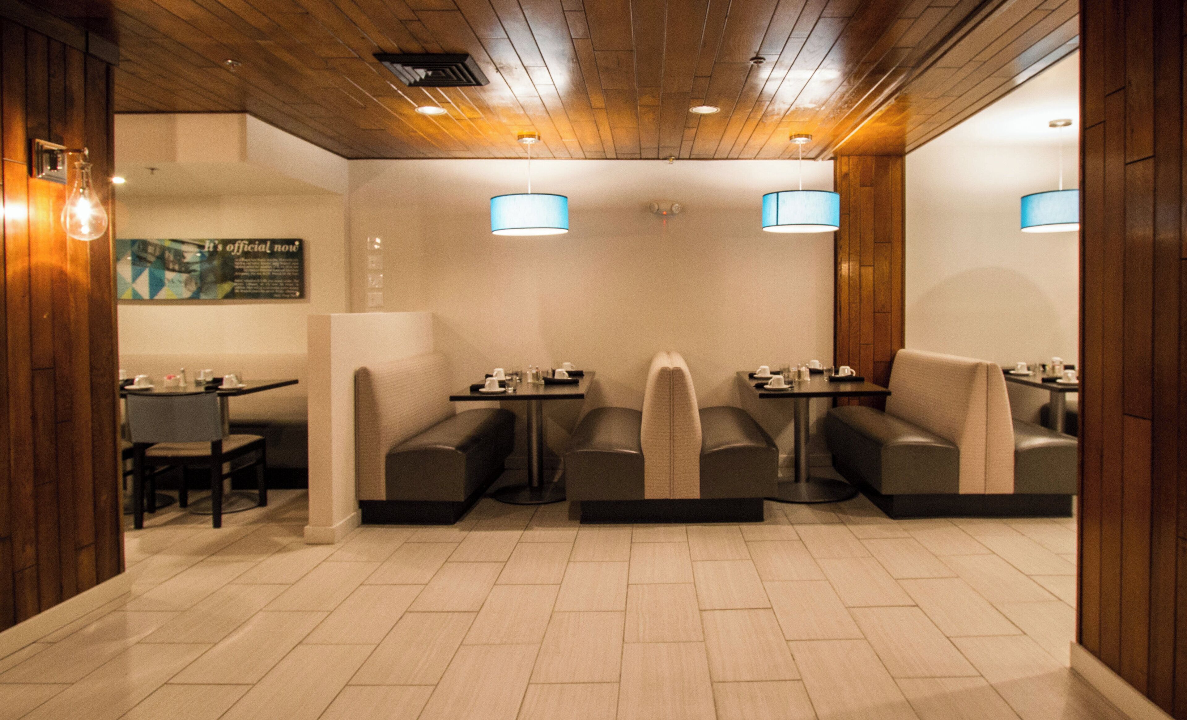 A restaurant with booth seating, tables, and hanging lamps.