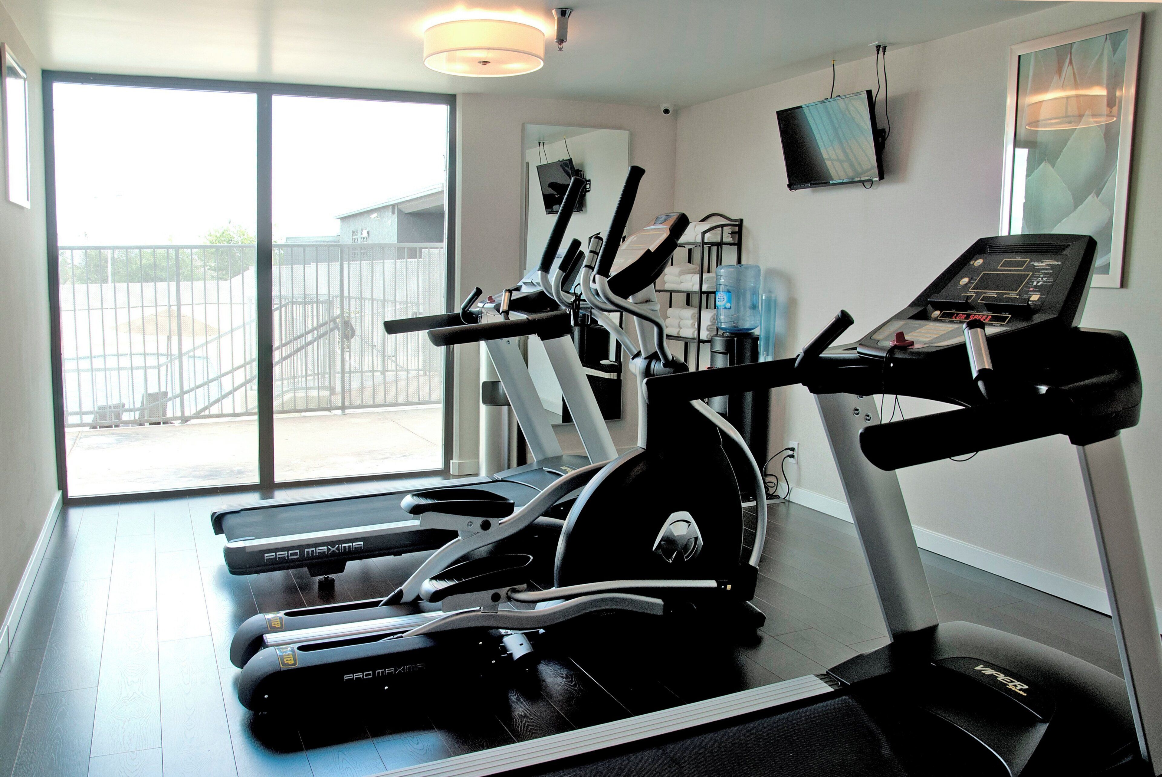 Una palestra con tapis roulant, cyclette e distributore d'acqua.