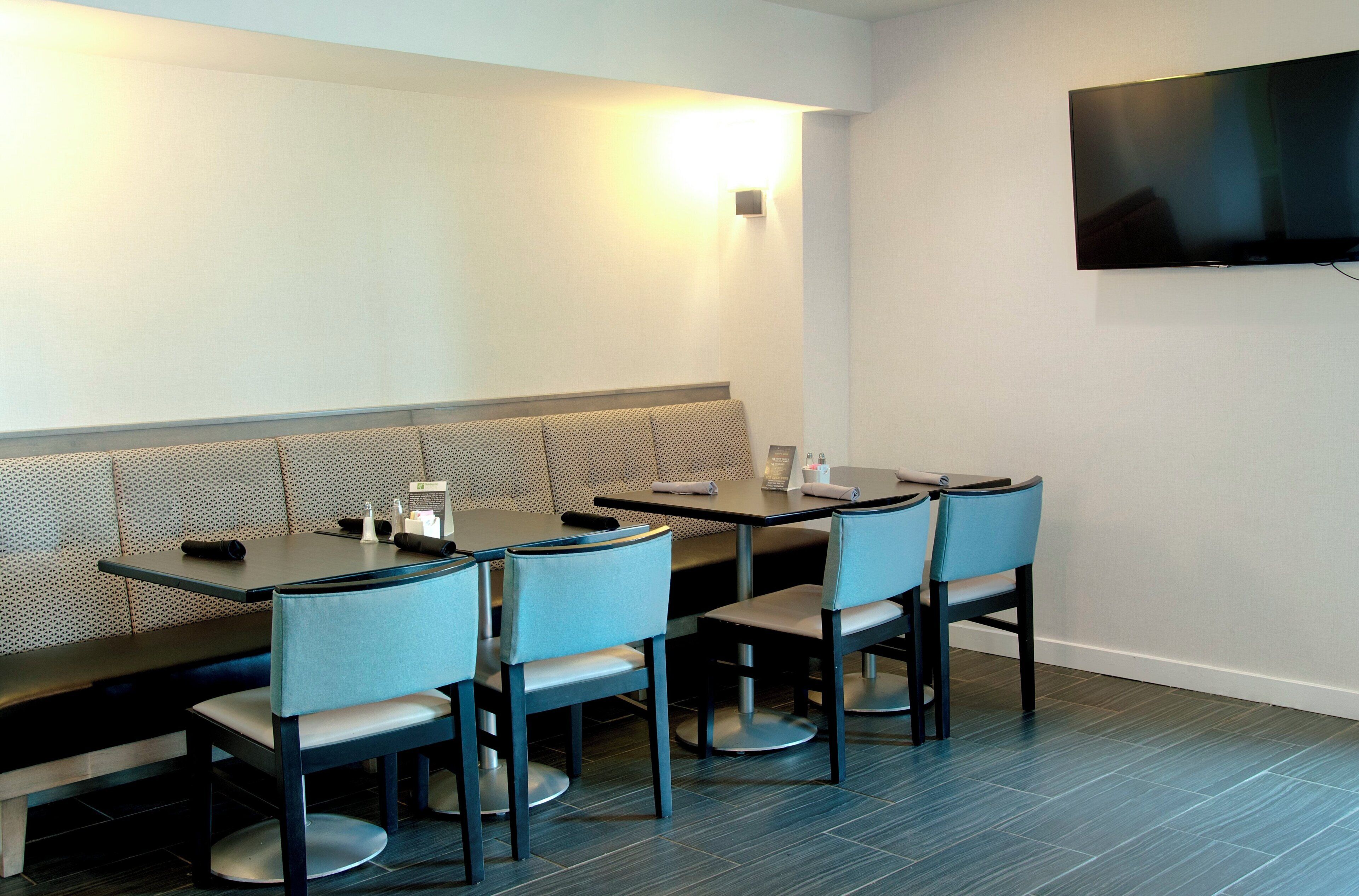 Un restaurant doté d’un long banc pour s’asseoir, d’un téléviseur à écran plat fixé au mur et d’un sol carrelé.
