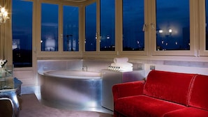 A modern bathroom with a large bathtub, a red sofa, and a glass table. - Papadopoli Hotel Venezia - MGallery Collection (Venice)