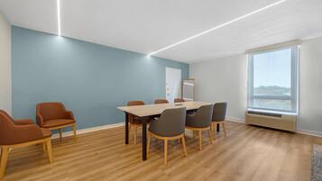 Une salle de conférence avec une table en bois, six chaises et un tableau blanc.