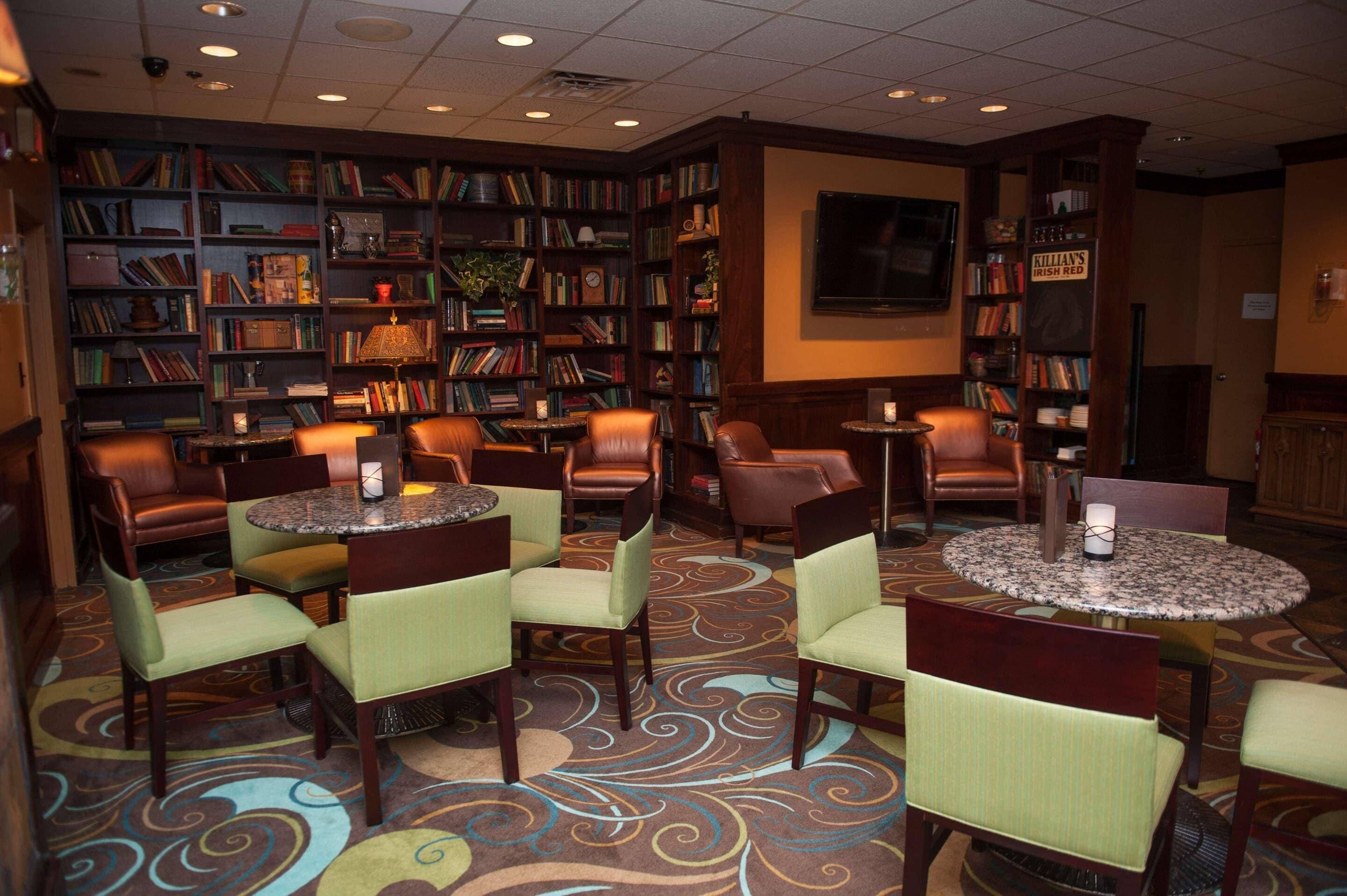 A library with bookshelves, leather chairs, and tables.