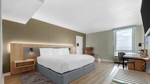 A modern bedroom with a large bed, bedside tables, a desk, and a chair.