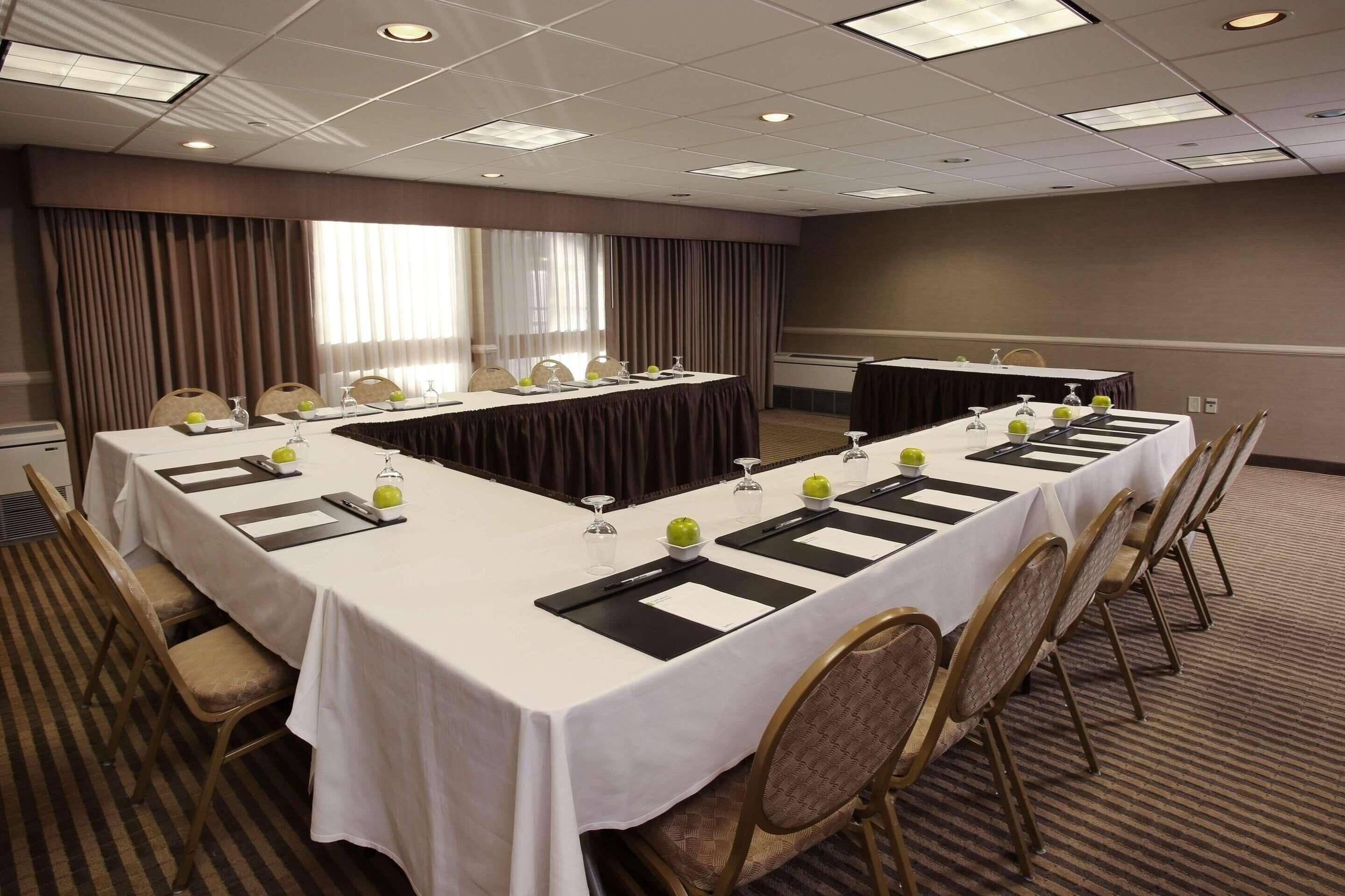 A conference room with a long table, chairs, and a projector screen.