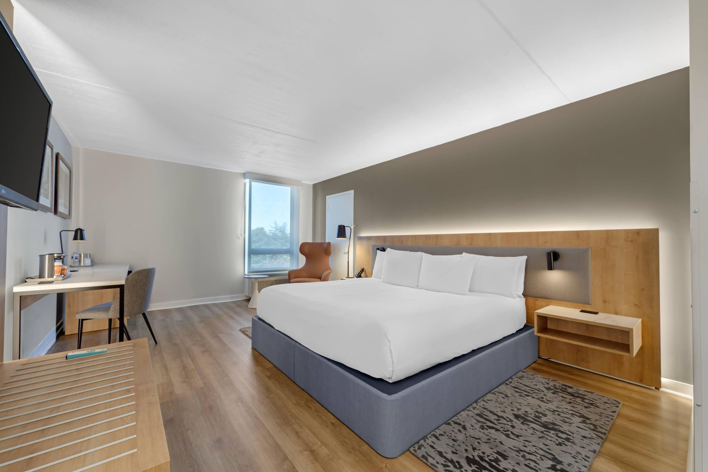 Ein modernes Schlafzimmer mit einem großen Bett, einem Schreibtisch und einem Sessel.