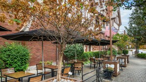 An outdoor cafe with tables and chairs, surrounded by brick buildings and trees. - Best Western Premier Mariemont Inn (Cincinnati)