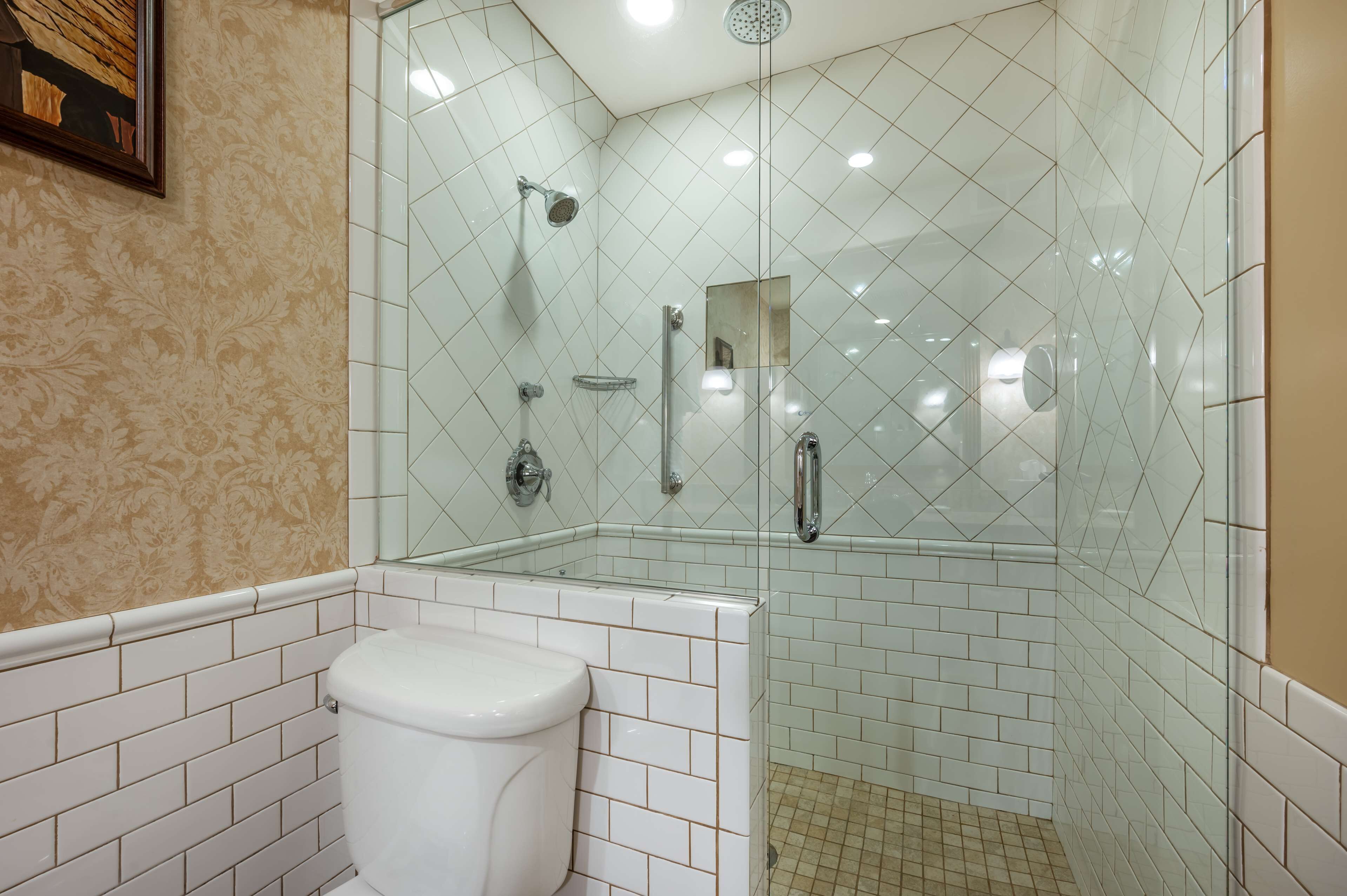 A bathroom with a glass-enclosed shower, a toilet, and a sink.