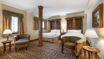 A hotel room with two beds, a large wooden pillar, patterned carpet, and classic furniture.