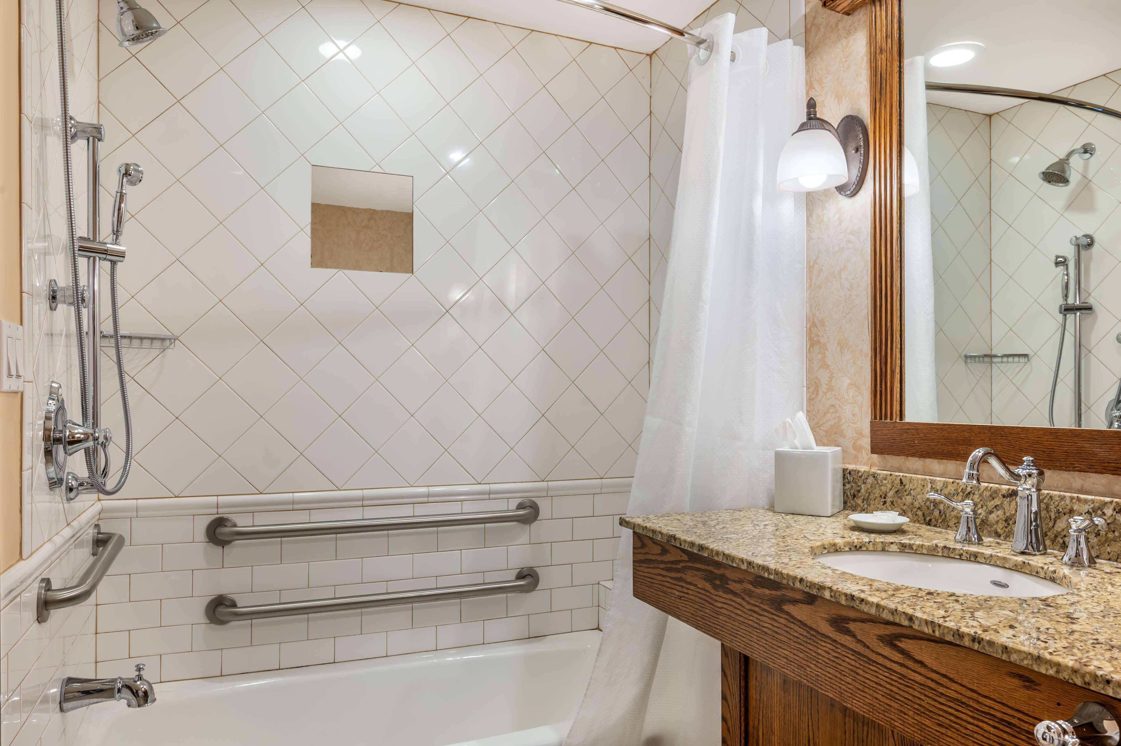 Une salle de bain moderne équipée d’une baignoire, d’une douche et d’un meuble-lavabo avec un évier et un miroir.