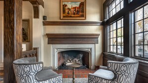 A room with a fireplace, two patterned armchairs, a small table, and a painting above the fireplace. - Best Western Premier Mariemont Inn (Cincinnati)