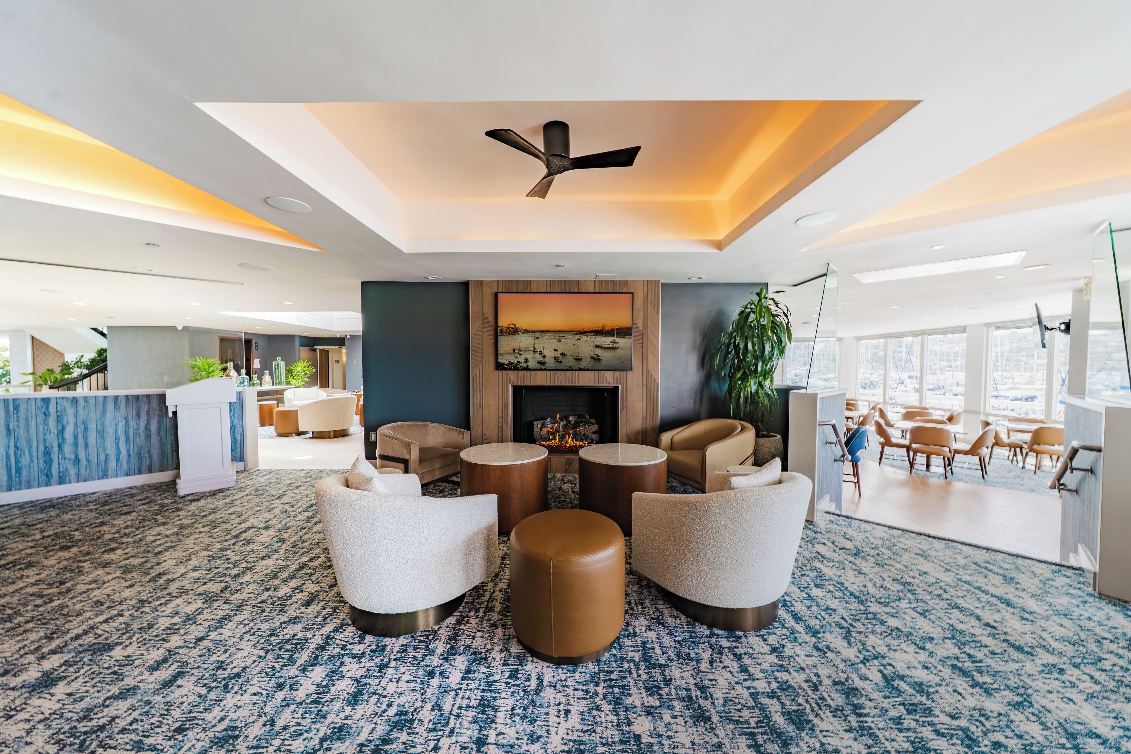 A spacious lobby with a central seating area, a fireplace, and a large window offering a view of the outdoors.
