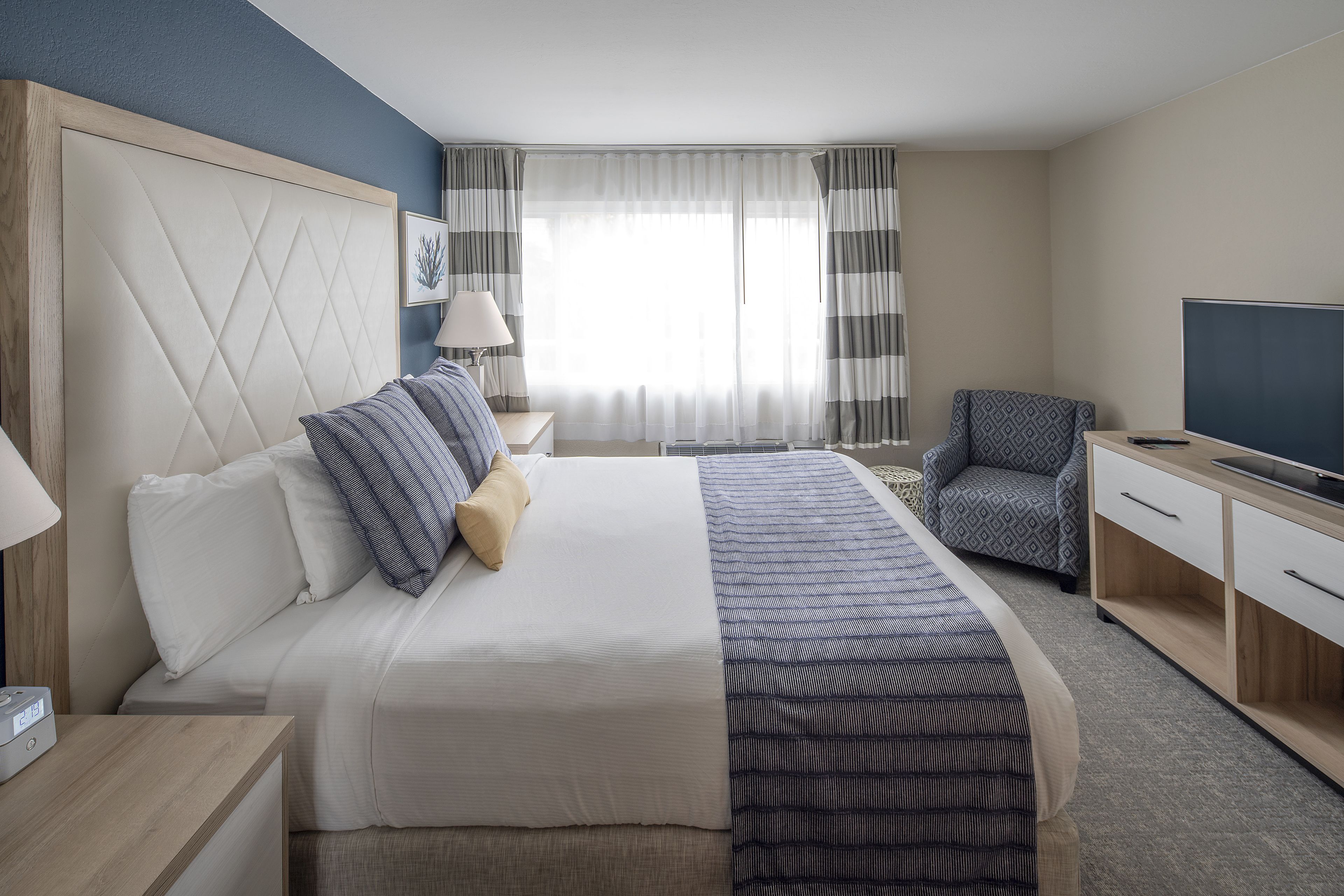 A hotel room with a large bed, a TV, a desk, and a chair.
