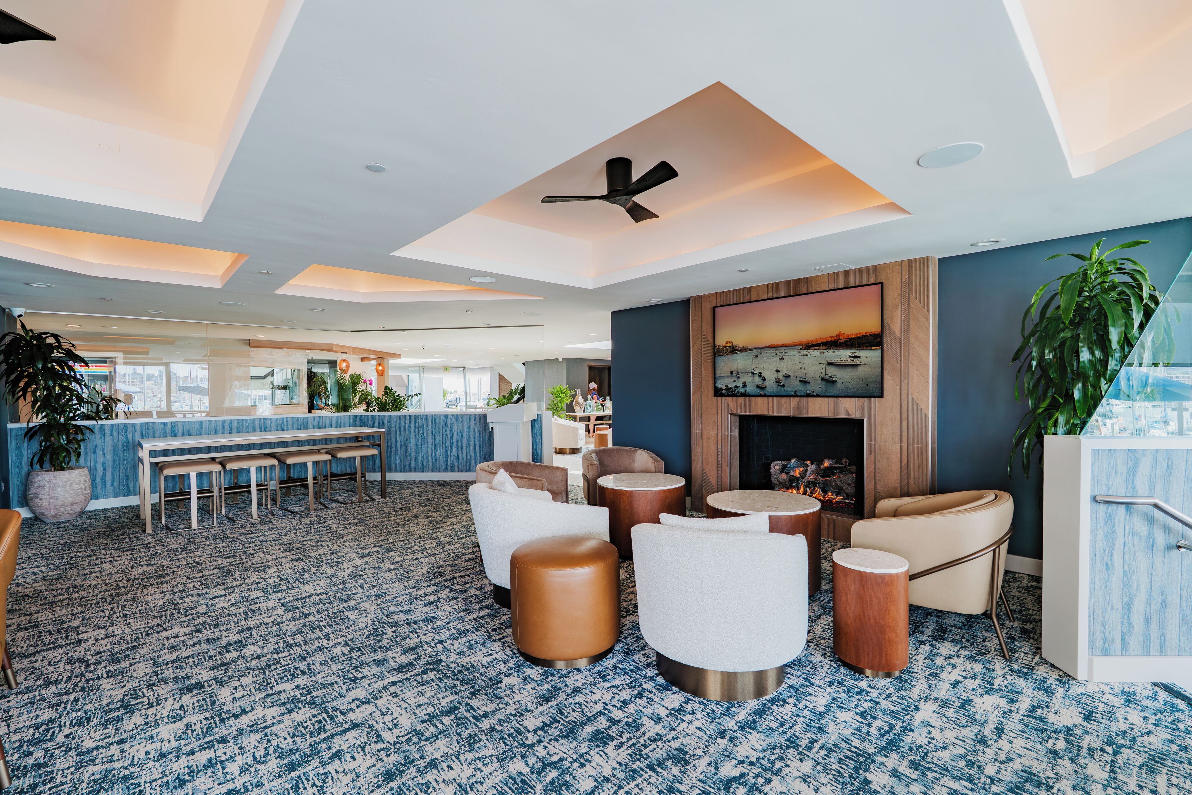 A modern lounge area with seating, a fireplace, and a view of the city.