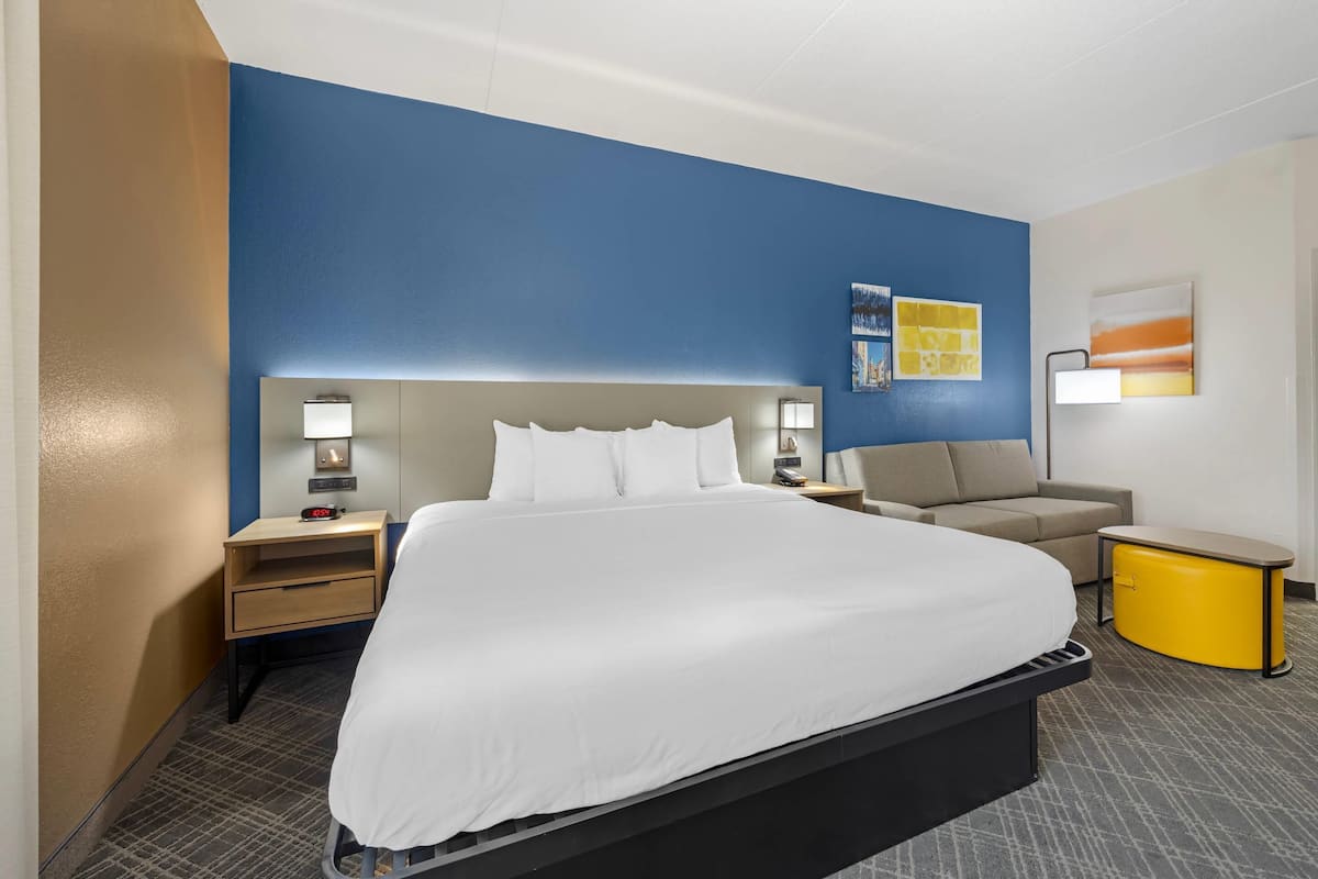A hotel room with a large bed, bedside tables, a desk, and a chair.