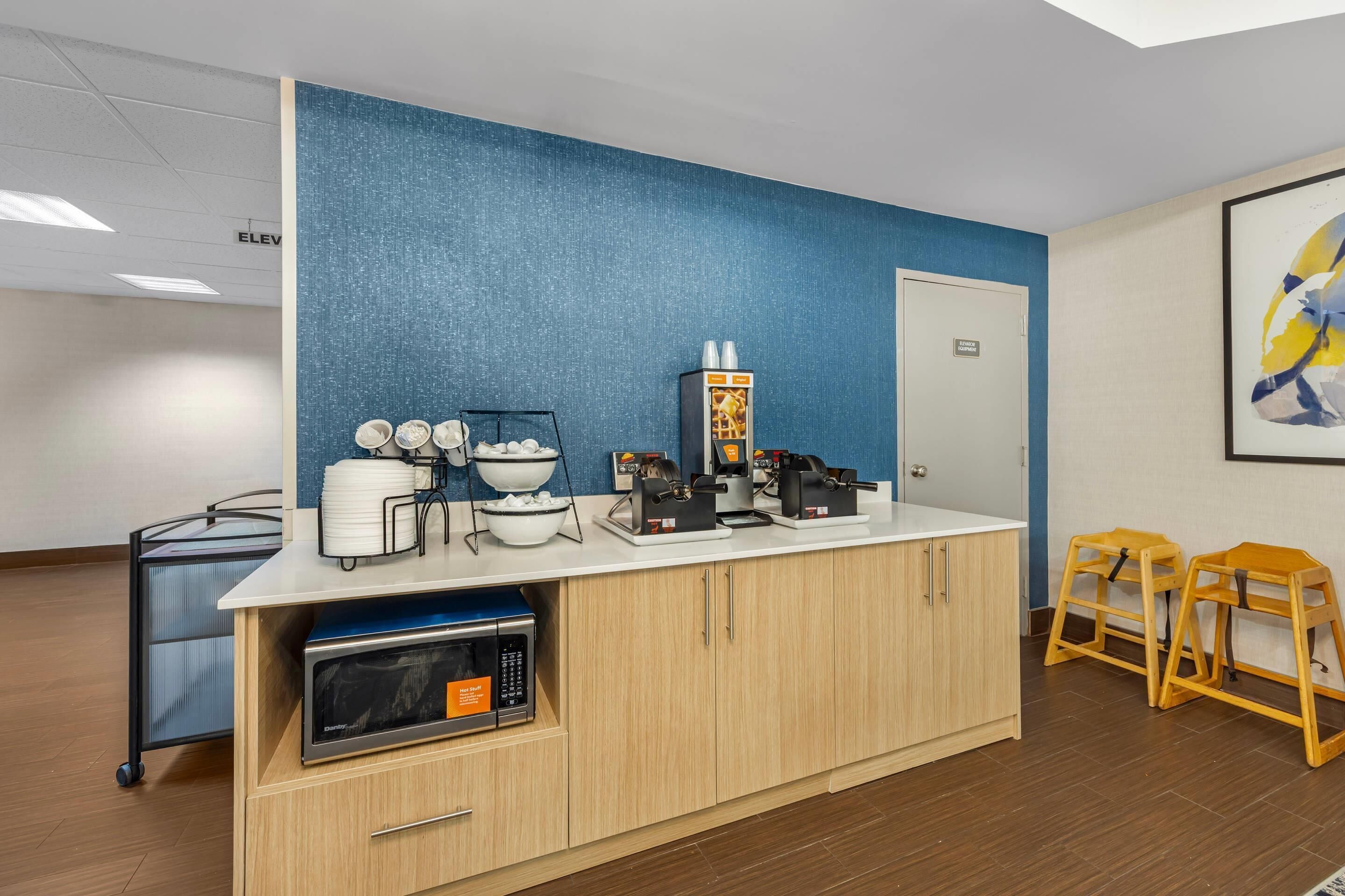 A kitchenette with a microwave, coffee maker, and bowls on a counter.