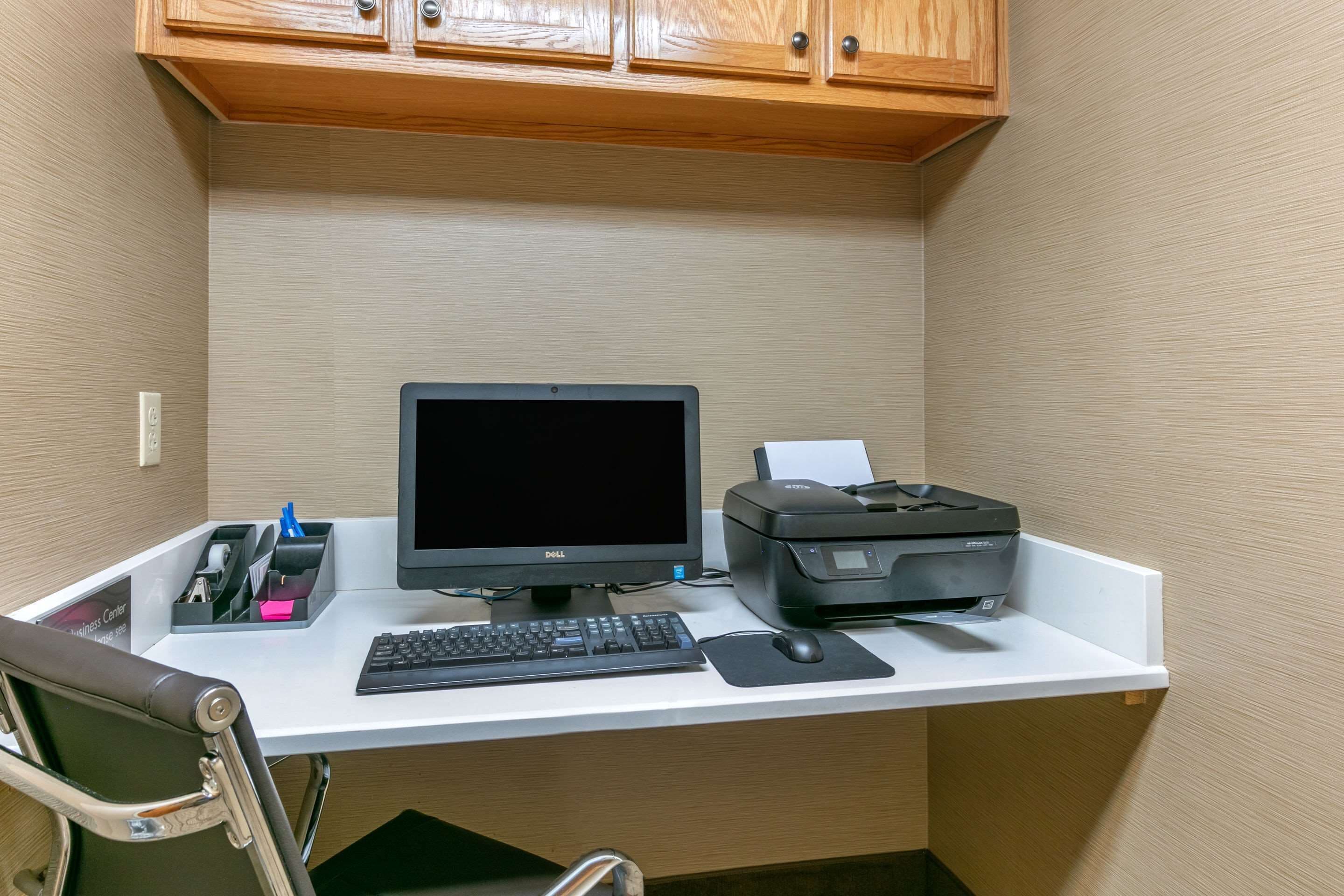 A small office space with a desk, computer, printer, keyboard, mouse, and chair.
