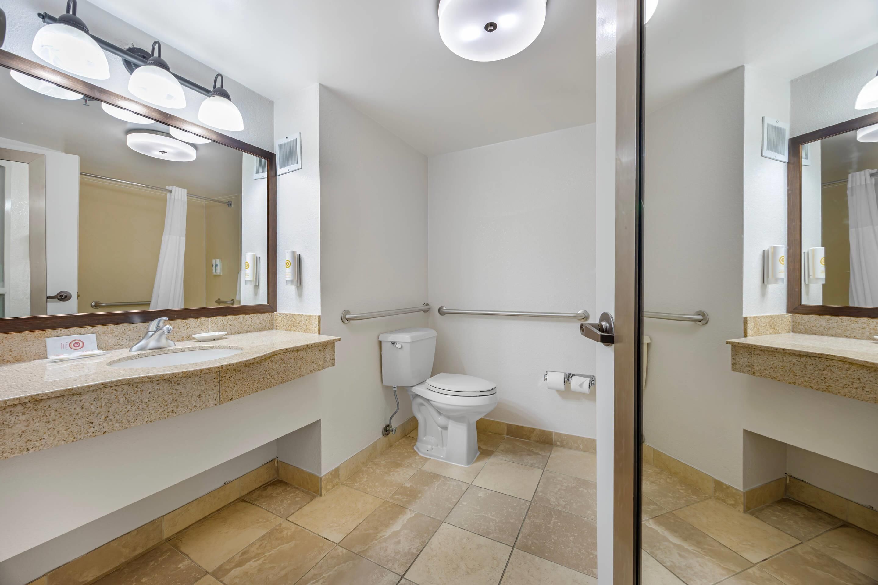 Et moderne badeværelse med toilet, vask med spejl og bruseområde.