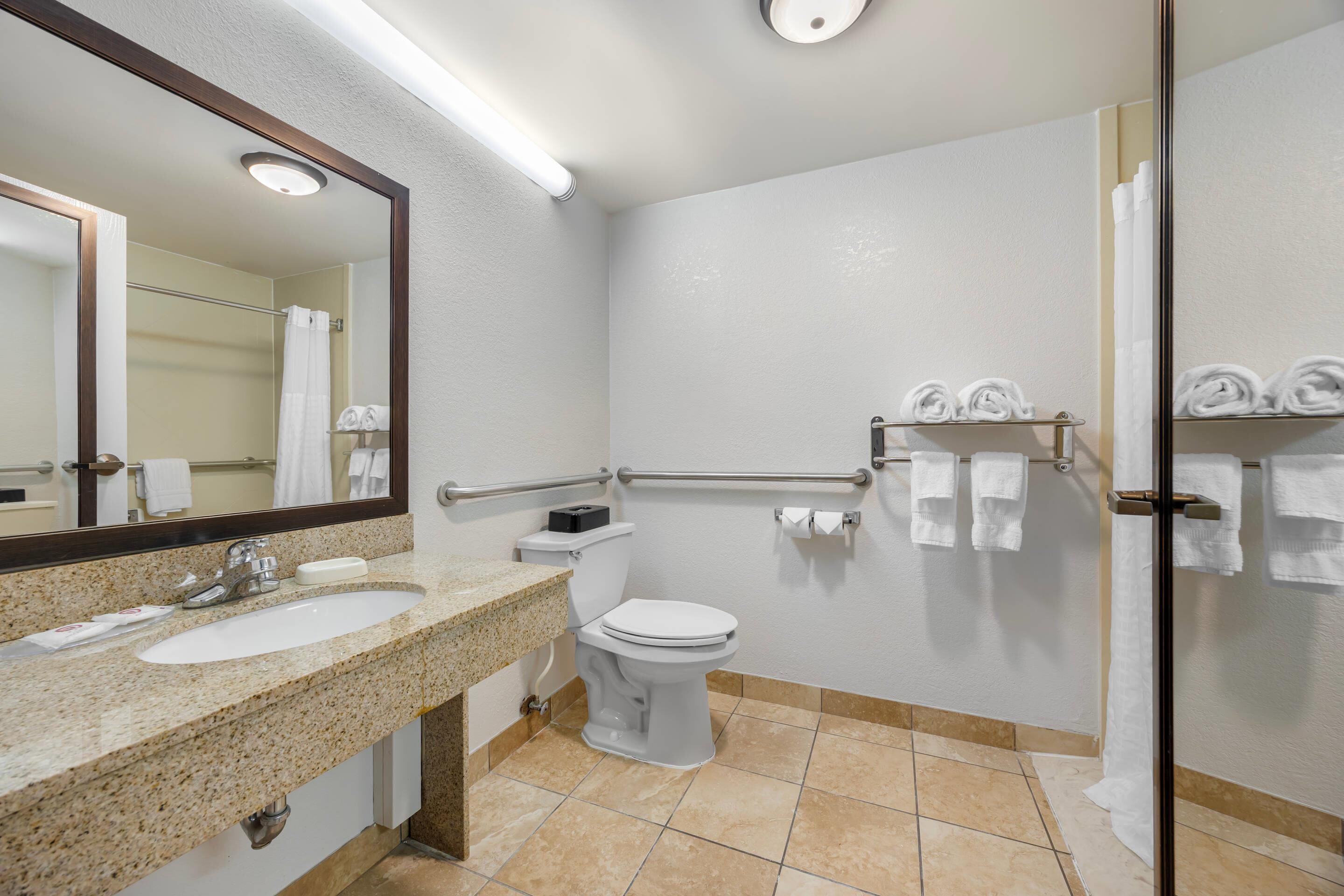 A bathroom with a sink, toilet, and shower area.