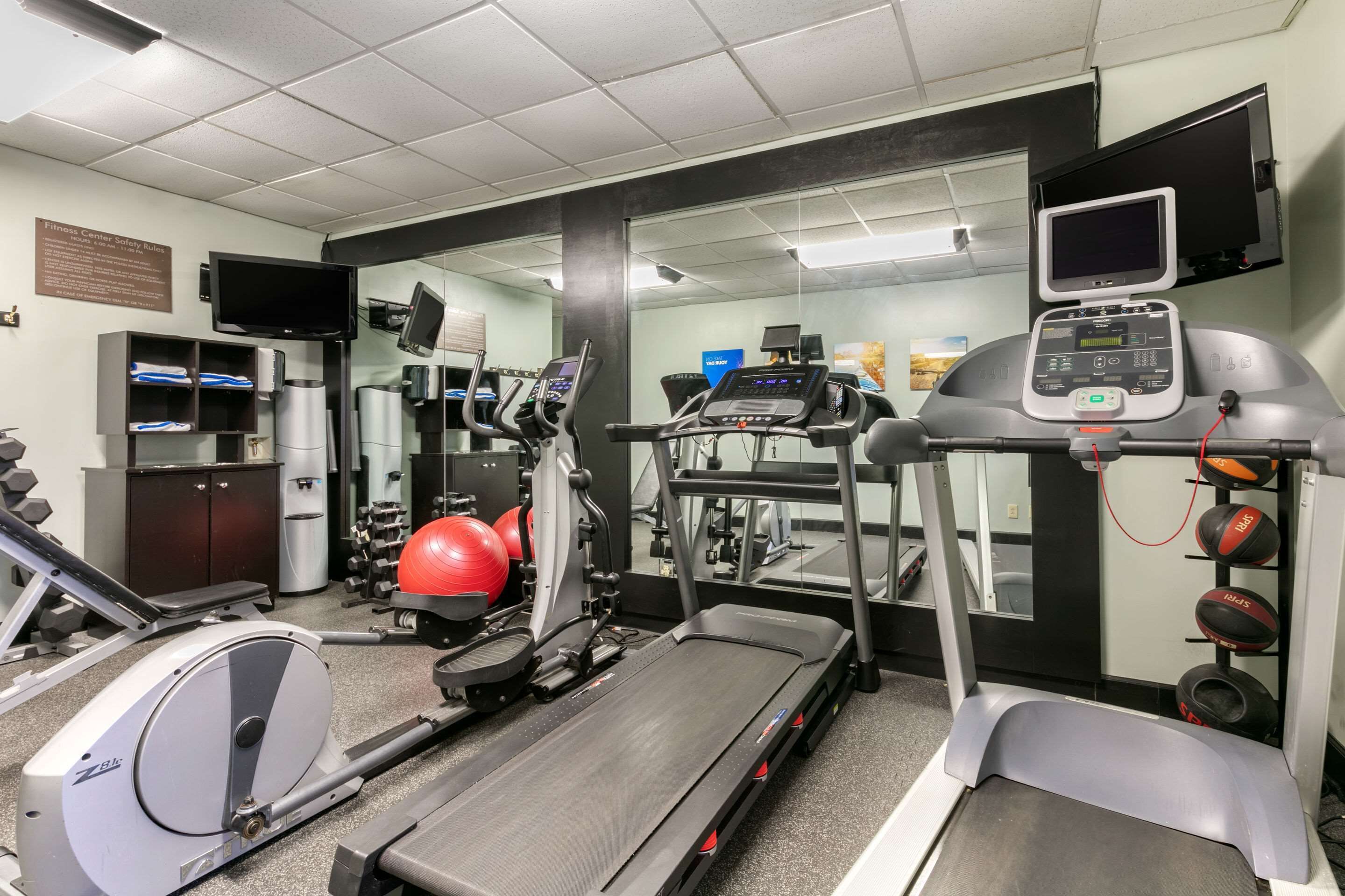 A gym with various exercise equipment including treadmills, a stationary bike, and free weights.