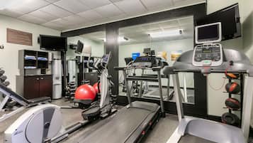 A gym with various exercise equipment including treadmills, a stationary bike, and free weights.