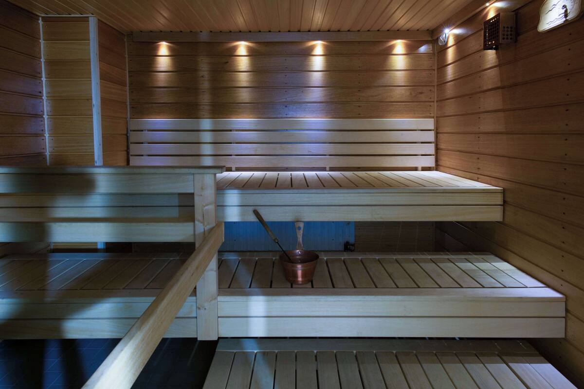 Eine Sauna mit Holzbänken und einem Kupferkübel.