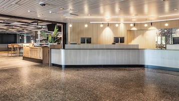Un espace d’accueil moderne avec un comptoir incurvé, un lambris en bois et un sol en pierre polie.