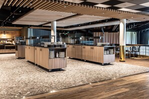 Un interior de restaurante moderno con armarios de madera, un mostrador central de servicio y un techo a cuadros.
