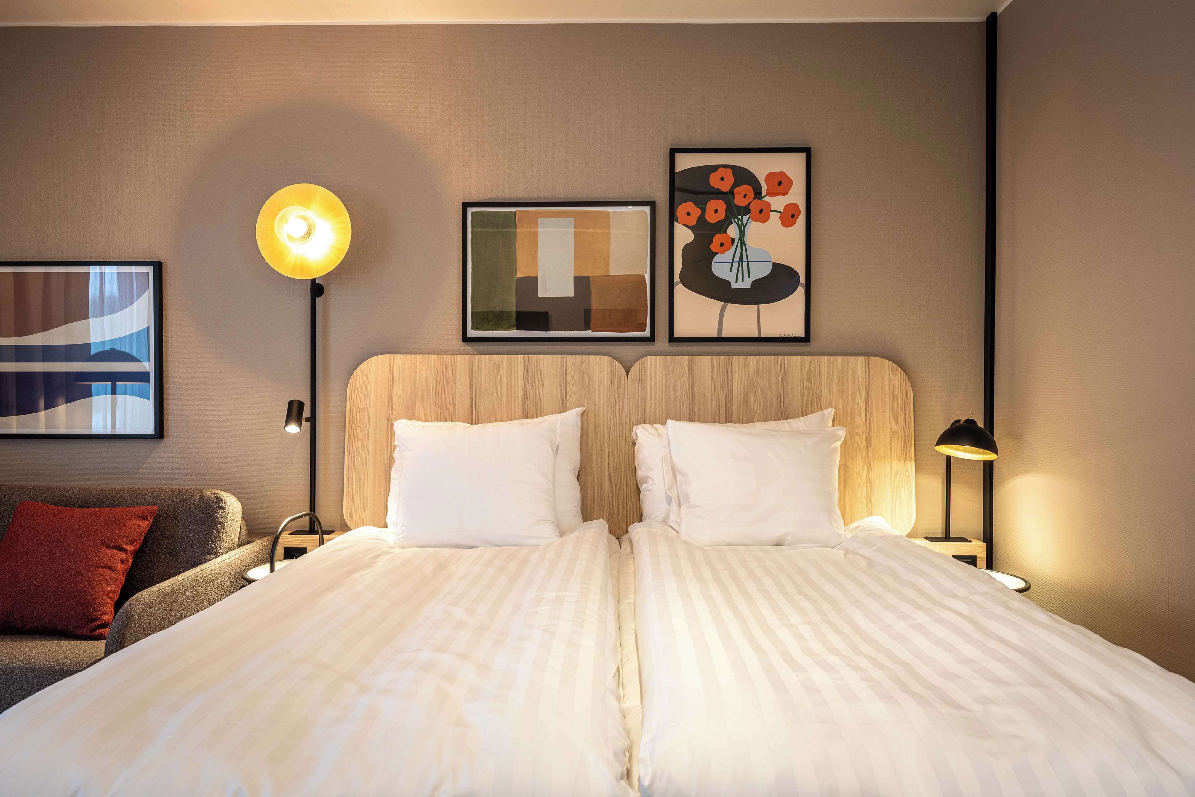 Een tweepersoonsbed met witte lakens, een houten hoofdbord en twee nachtkastjes met lampen.