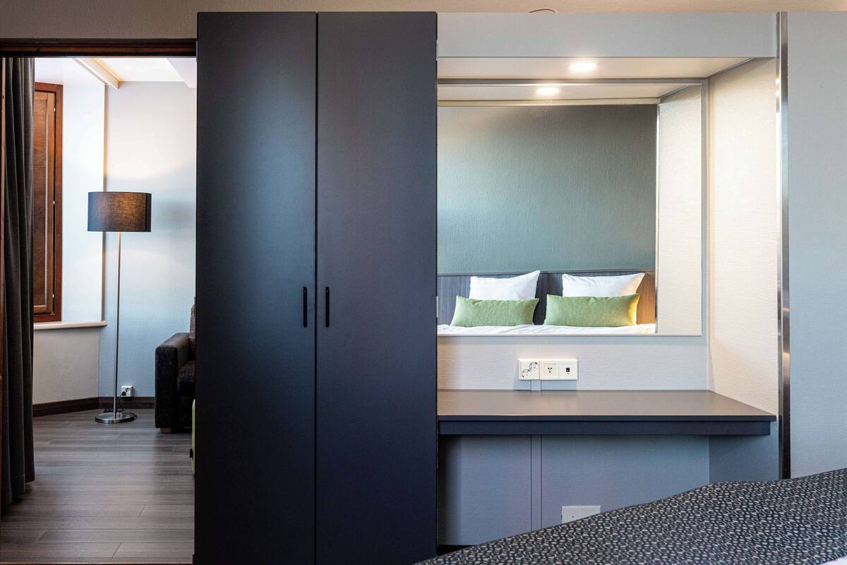 Ein modernes Hotelzimmer mit Schreibtisch, großem Kleiderschrank und einem Fenster mit Blick.