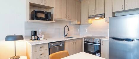 Una cocina moderna con armarios de madera, un refrigerador de acero inoxidable, un microondas, una cafetera y un lavavajillas.