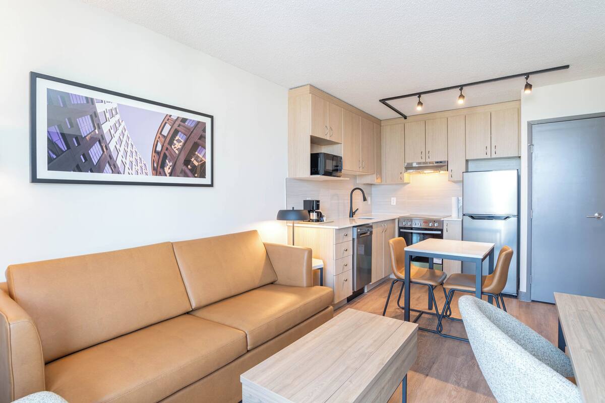 Un espacio habitable pequeño con sofá, mesa de comedor y kitchenette.
